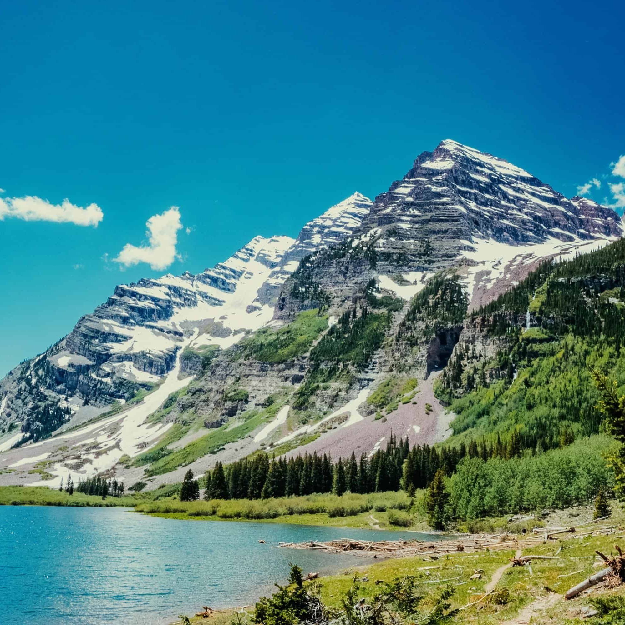 Colorado mountains next to a lake and forested area. Bright blue sky.
